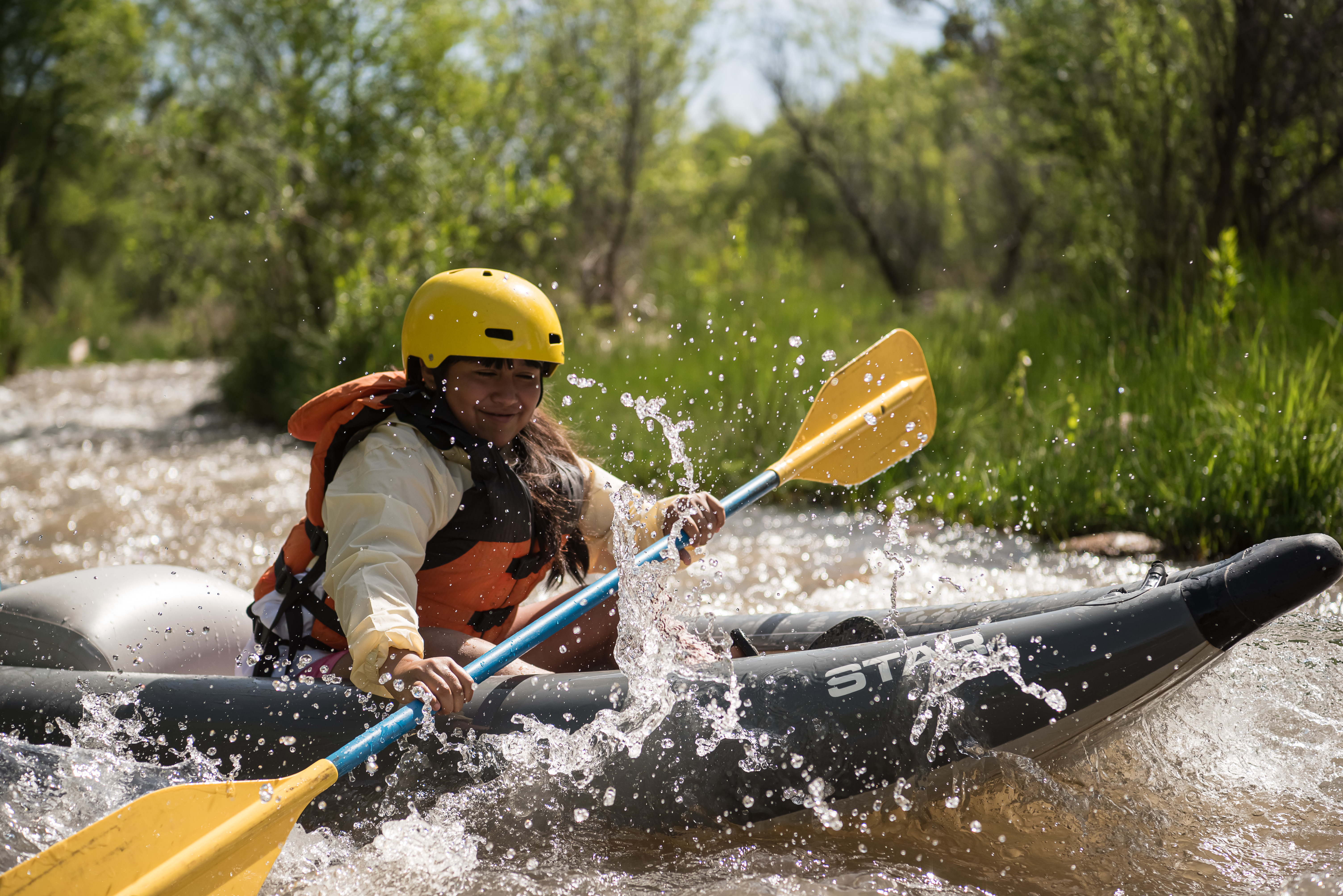 a young paddler smiles as water splashes into them